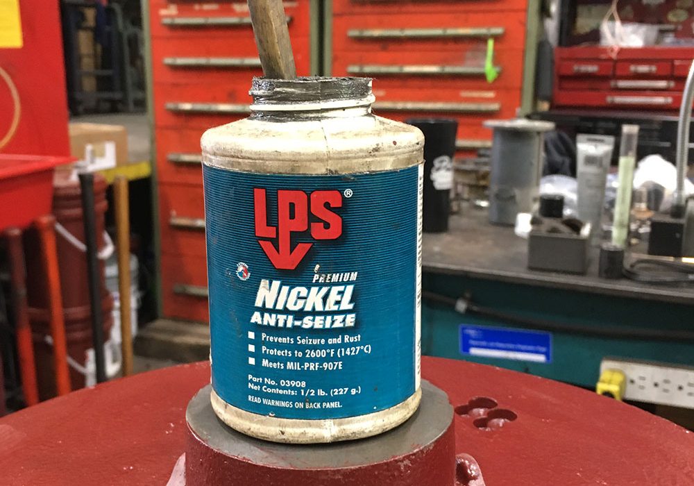 jar of nickel anti-seize sitting on top of a compressor motor in a repair shop
