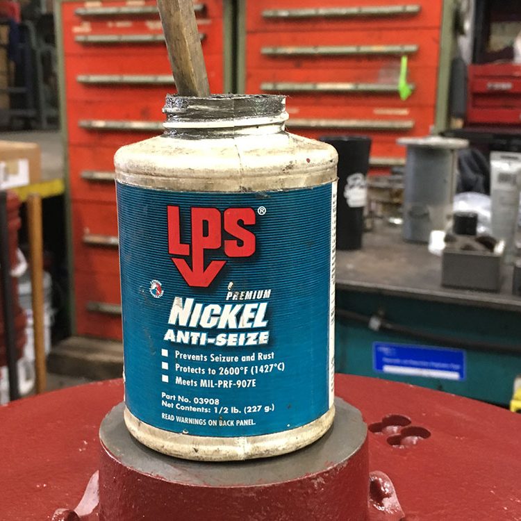 jar of nickel anti-seize sitting on top of a compressor motor in a repair shop